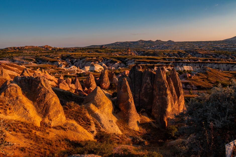 Stunning view of Cappadocia's fairy chimneys at sunset, showcasing the unique geological formations and landscape of Nevşehir, Turkey.
