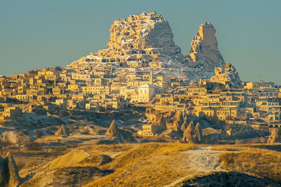 Stunning sunrise view of Uçhisar Castle, Göreme, Türkiye with unique rock formations.