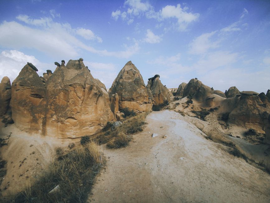 Explore the breathtaking rock formations and arid landscape of Cappadocia under a clear blue sky.